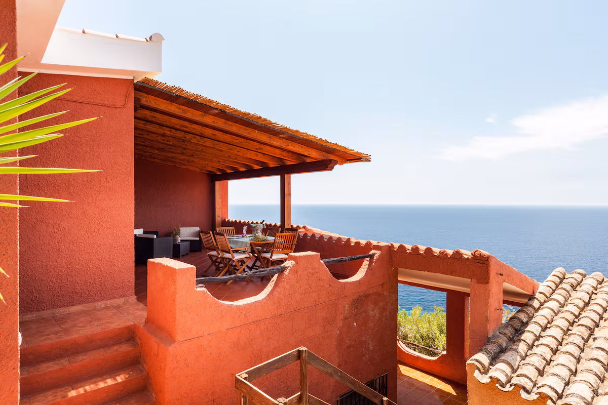The pergola-covered terrace with its outdoor dining table, facing the open sea